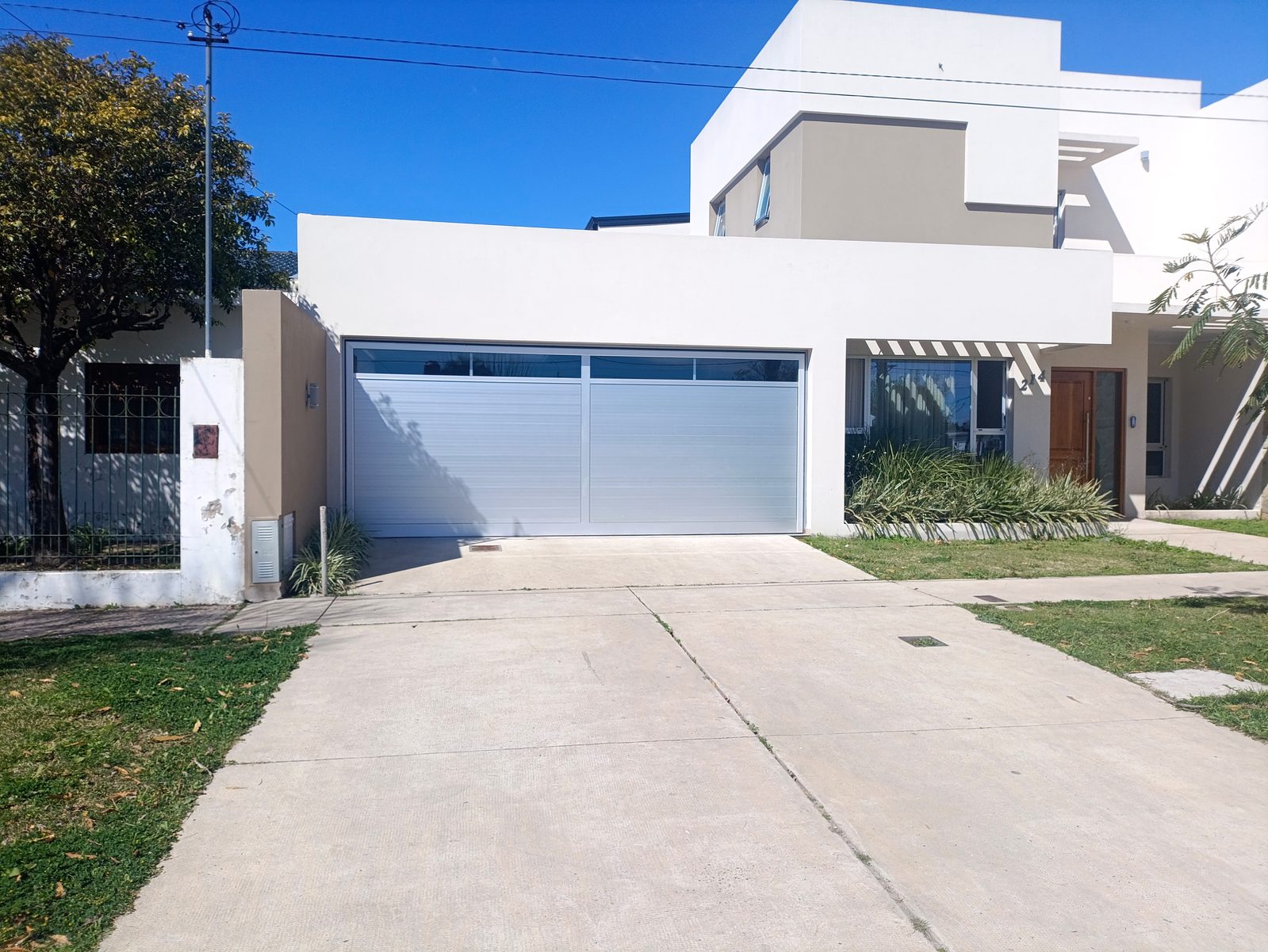 Portón seccional de aluminio blanco con paño vidriado